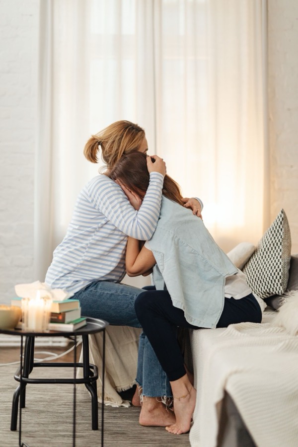 A mother comforting her child on the couch in soft evening light