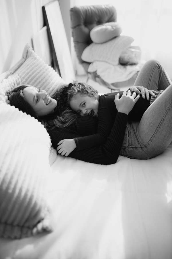 A mother and daughter laughing together on a bed